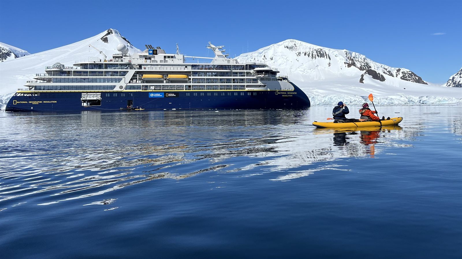 Foto do navio National Geographic Resolution em aguas antarticas, com dois caiaques em primeiro plano na baia de Borgen.